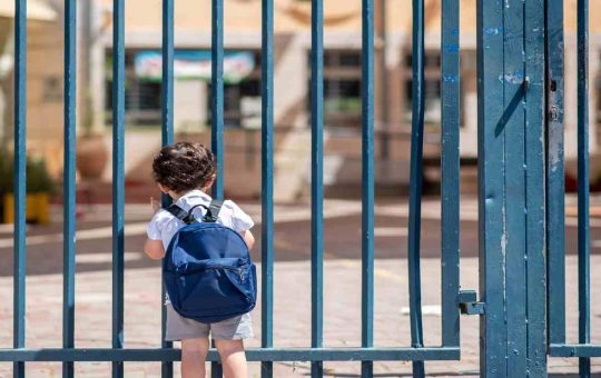 Bambino davanti alla scuola chiusa